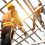 Construction workers wear safety straps while working on the building's roof structure at a construction site. Roofer using a pneumatic nail gun.
